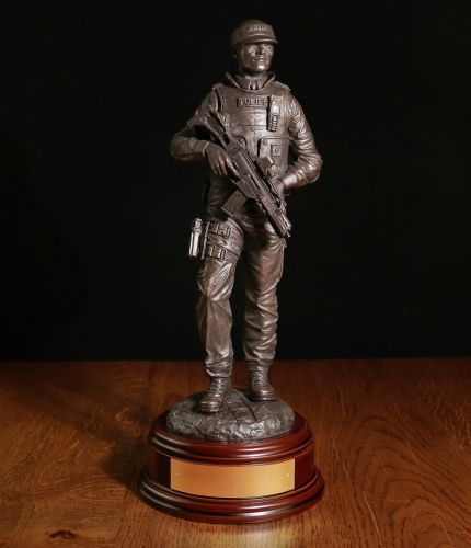 A hand made bronze cold cast resin statue of a Modern Male British Armed Police officer on foot patrol. In this sculpture he's wearing a police issue baseball cap. We include the standard wooden base and an engraved brass plate