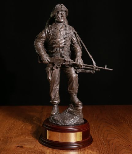 12" scale cold cast bronze resin sculpture of a British Army Soldier carrying a GPMG on patrol. We include the wooden base and engraved brass plate.