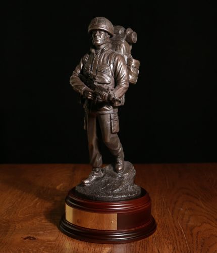 A cold cast bronze statuette of a British Army Soldier in full "Marching Order" on patrol, walking downhill, Bergan, PLCE & SA80 Rifle. We include this wooden base, a free badging service and an engraved brass plate as standard.