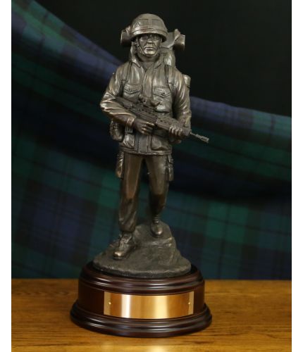 A cold cast bronze resin statuette of a British Army Soldier in full "Marching Order" on patrol, walking downhill, Bergan, PLCE & SA80 Rifle. We include this wooden base, a free badging service and an engraved brass plate as standard.