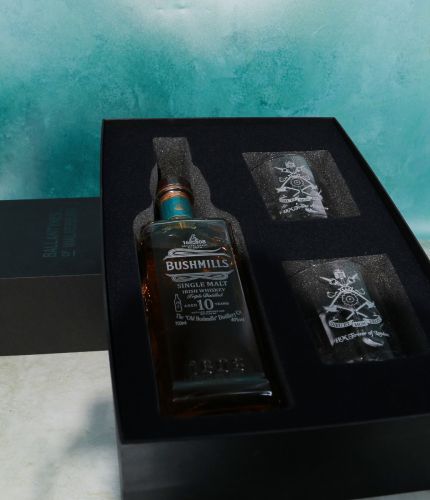 An engraved bottle of 10 Year old Bushmills Single Malt Irish Whiskey and two panel style 10oz crystal whisky tumblers. The set is completed within a black cut out presentation box. We provide you with images to approve.