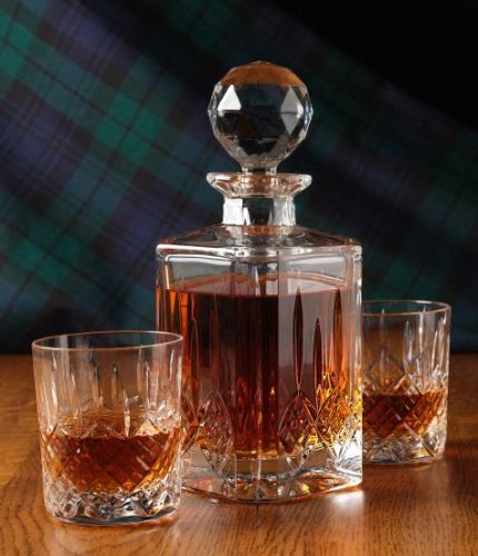 A fully cut whisky crystal hosting set consisting of a decanter and two tumblers. The set is presented inside a dark blue satin lined presentation box.