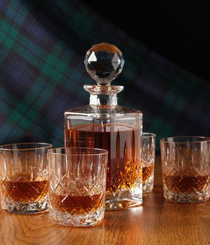 A fully cut whisky crystal hosting set consisting of a whisky decanter and four tumblers. The set is presented inside a dark blue satin lined presentation box.