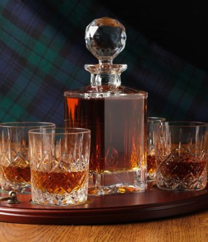 A 24% lead crystal panel cut square decanter and four fully cut whisky tumblers on a serving tray. We can offer a personalised engraving on the front of the decanter and brass plate on the wooden tray with this set.