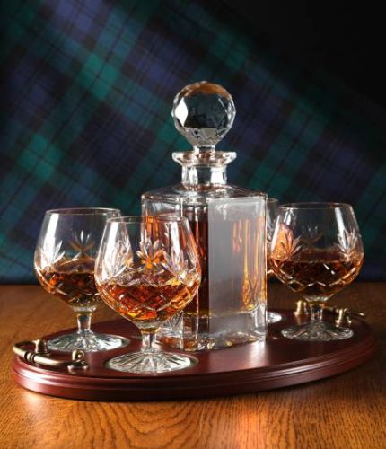 A 24% lead crystal panel cut square decanter and four fully cut brandy goblets on a serving tray. We can offer a personalised engraving on the front of the decanter and an engraved brass plate on the wooden tray with this set.