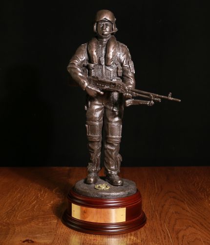 This is an 12" scale sculpture of a Military Helicopter GPMG Gunner. Dressed in a flight suit and helmet, he is carrying a GPMG with his SA 80 slung on his back. Wooden base and an engraved plate are included