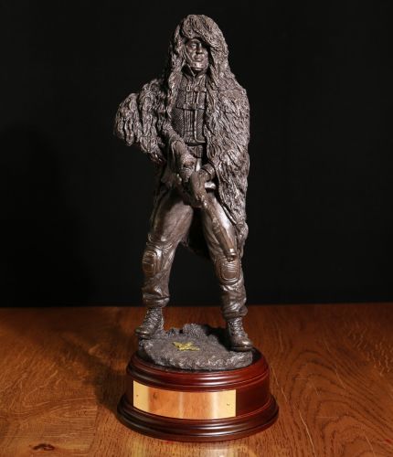A 12" scale sculpture of a Parachute Regiment Sniper with the L115A3 Rifle. He cammed up with a ghillie suit on. We offer a choice of wooden bases and free engraving