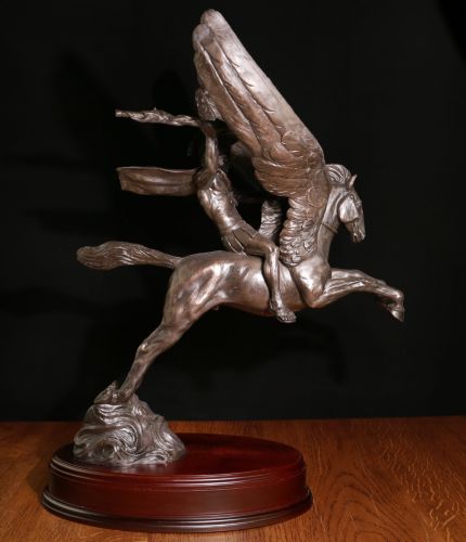 Bellerophon - ‘the slayer of enemies’, astride his winged steed Pegasus. Without the wooden base this sculpture is 18" Tall, 16" from nose to tail and 14" from wingtip to wingtip. We offer a choice of wooden bases.