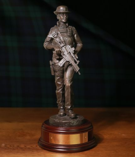 A bronze cold cast resin statue of a Modern Female British Armed Police officer on foot patrol. She's wearing a police issue bowler style hat. The sculpture is 12 Inches tall, we include the standard wooden base and an engraved brass plate.