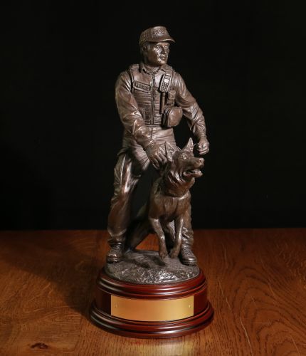 A Modern K9 British Police Officer with his German Shepherd Dog to hand. The sculpture is 12 Inches tall, we include the standard wooden base and an engraved brass plate as standard.