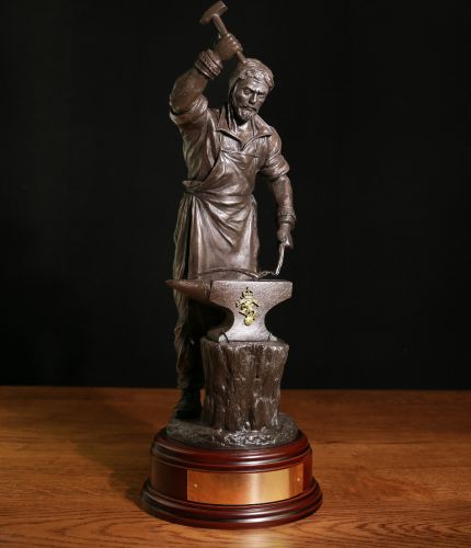 This is a 12" scale sculpture depicting St Eligius as a Craftsman working as a blacksmith and armourer beating out a sword blade. We complete the sculpture with a choice of finish, a wooden base and a fully engraved nameplate on the front of the base.