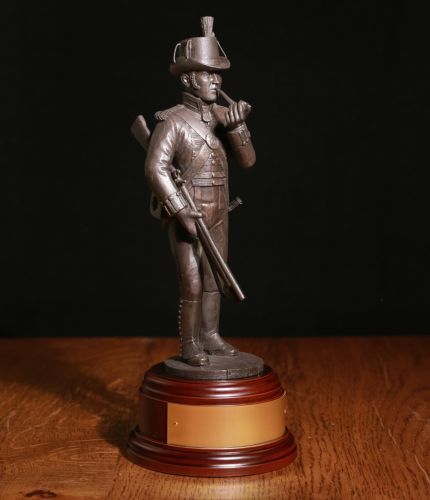 This 8" sculpture depicts a marine sharpshooter of 1805. We include the wooden base seen here as standard, and also offer a free engraved brass plate if requested.