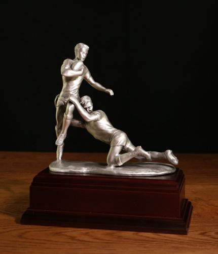 A 'try saving tackle'. The two players are sculpted in a 6" scale. The overall height of the piece on its base is 8.5" tall. It's cast in pure lead free pewter and we buff it to create this lovely finish. On the wooden base there is space to mount your ow