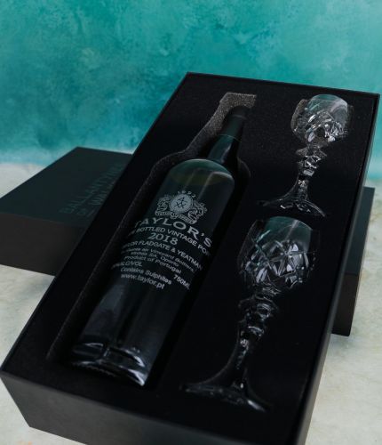 An engraved 75cl Bottle of Taylor's Late Bottled Vintage Port and two fully cut crystal port glasses in a black foam cut out gift box. The Bottle can be engraved, but as they are fully cut, the glasses are facetted all round. 